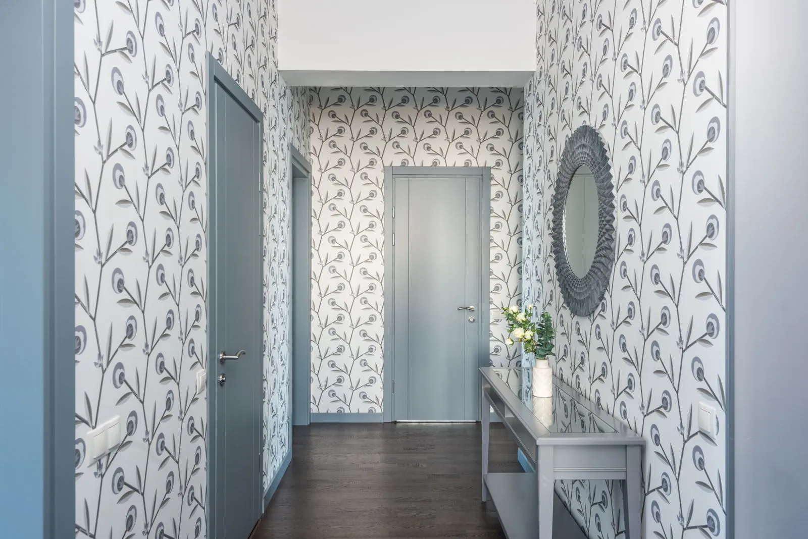 Entrée étroite avec miroir, banc à chaussures, patères murales et couleurs claires pour paraître plus grande.